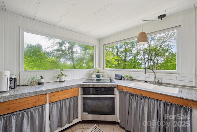 kitchen featuring black electric stovetop, a sink, tile counters, stainless steel oven, and light tile patterned floors