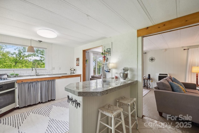 kitchen with a sink, plenty of natural light, tile countertops, and wall oven