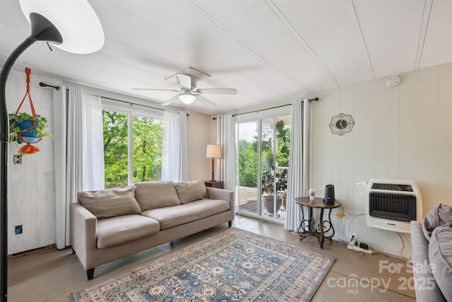 living area with heating unit, ceiling fan, and a textured ceiling