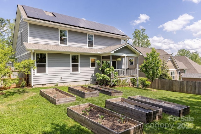 back of house with fence, crawl space, a garden, solar panels, and a yard