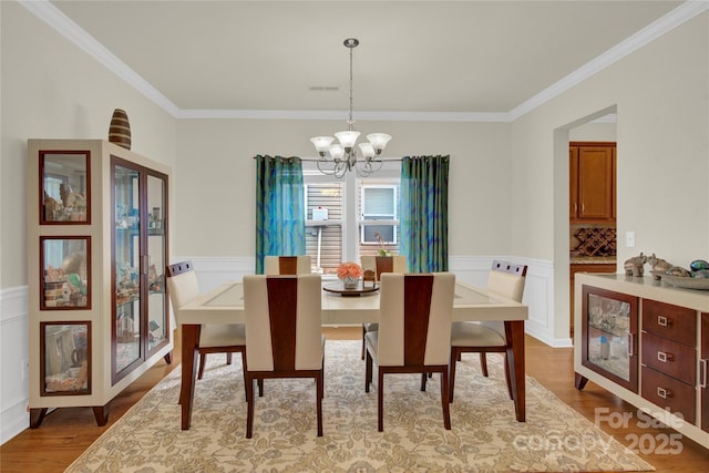 282 Fischer Rd, Fort Mill, SC 29175 - dining space with a chandelier, crown molding, wood finished floors, and a wainscoted wall