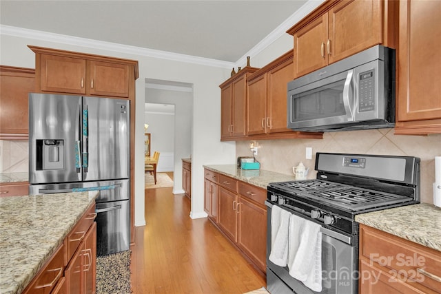 282 Fischer Rd, Fort Mill, SC 29175 - kitchen with appliances with stainless steel finishes, light wood-style floors, ornamental molding, decorative backsplash, and light stone counters