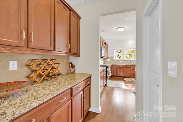 282 Fischer Rd, Fort Mill, SC 29175 - kitchen with stainless steel appliances, ornamental molding, decorative backsplash, light stone counters, and light wood-style floors