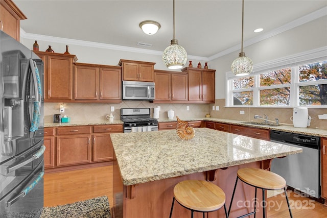 282 Fischer Rd, Fort Mill, SC 29175 - kitchen featuring appliances with stainless steel finishes, a sink, brown cabinetry, light stone counters, and a center island