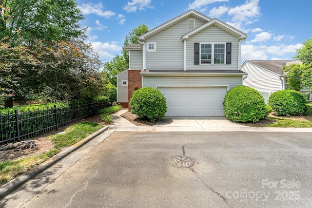 traditional home with an attached garage, concrete driveway, brick siding, and fence