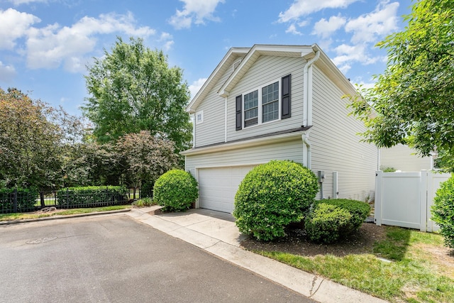 view of home's exterior with fence, a garage, and concrete driveway