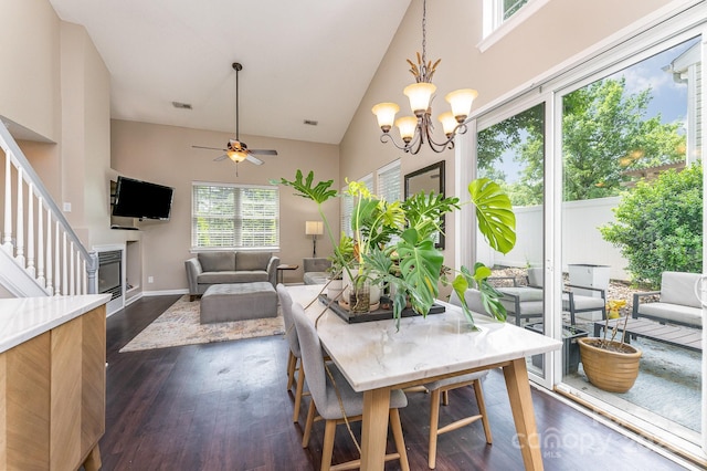 dining area with dark wood finished floors, visible vents, ceiling fan with notable chandelier, and high vaulted ceiling