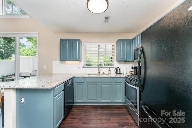 kitchen with a peninsula, blue cabinetry, black appliances, and a sink