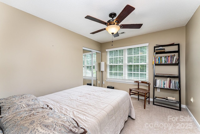 bedroom with light carpet, baseboards, a ceiling fan, and multiple windows