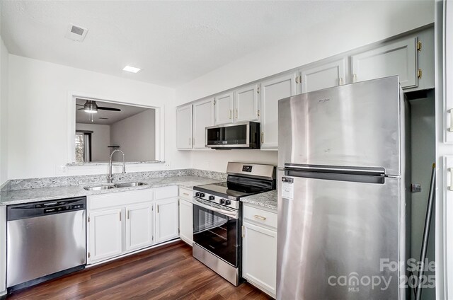 kitchen featuring stainless steel appliances, a sink, dark wood-style floors, ceiling fan, and light stone counters