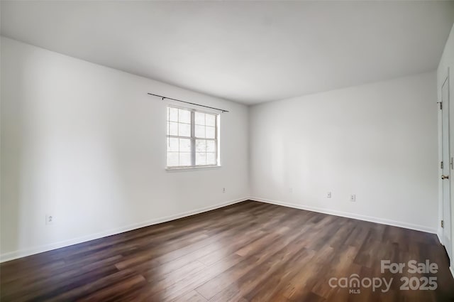 unfurnished room featuring dark wood-type flooring and baseboards