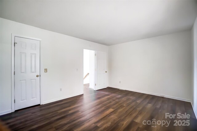 spare room featuring dark wood-style floors and baseboards