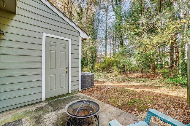 view of outdoor structure featuring an outdoor fire pit, central air condition unit, and an outbuilding