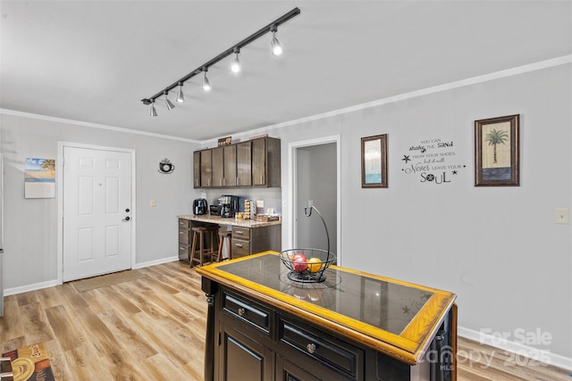 1792 Hoffman Rd, Gastonia, NC 28054 - kitchen featuring crown molding, rail lighting, light wood-type flooring, dark brown cabinetry, and light countertops