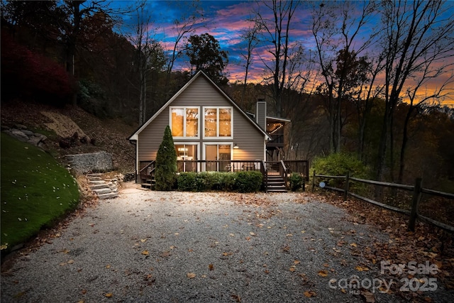 view of front of home with fence, a chimney, a deck, and stairway