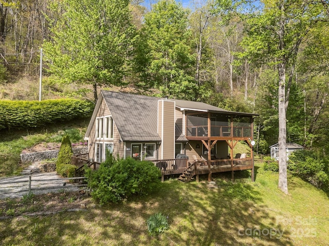 back of house featuring a deck, a chimney, a lawn, an outbuilding, and a wooded view