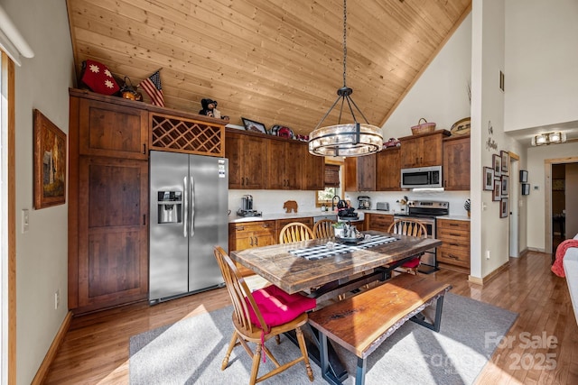 dining room with light wood-style floors, high vaulted ceiling, baseboards, and wood ceiling