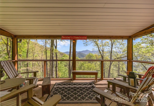 sunroom / solarium featuring a mountain view, lofted ceiling, and floor to ceiling windows