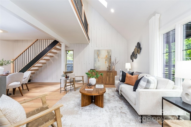 living area with lofted ceiling, stairway, and wood finished floors