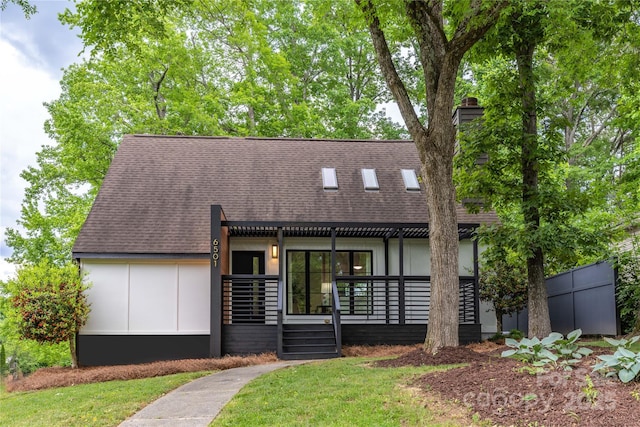 view of front of home with roof with shingles and a front lawn