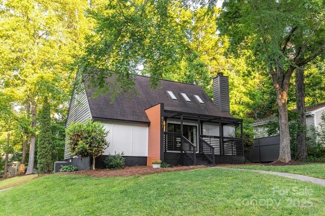view of front of property featuring a front lawn, roof with shingles, a chimney, and central air condition unit