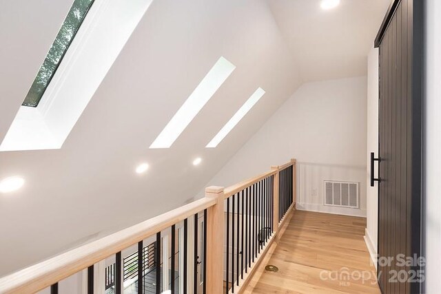 additional living space featuring a skylight, lofted ceiling, light wood-type flooring, and recessed lighting