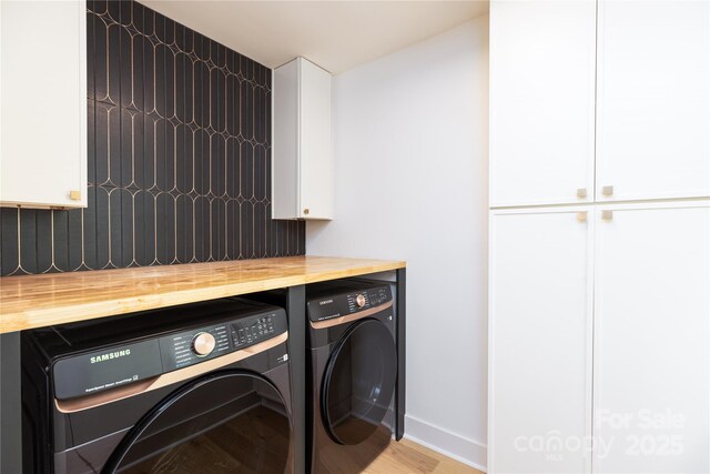 laundry area with cabinet space, washer and clothes dryer, wood finished floors, and baseboards