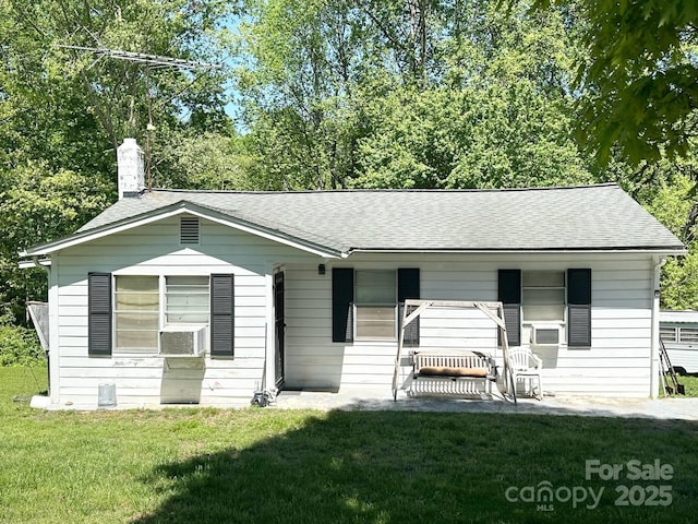 view of front of home featuring a front yard, a chimney, a patio area, and roof with shingles