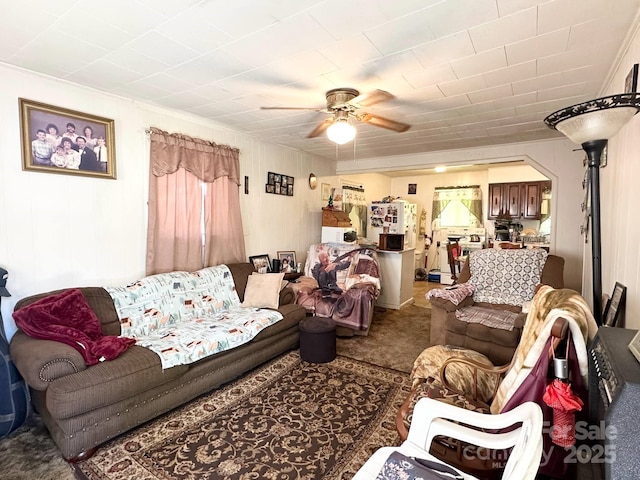 living area with crown molding, carpet floors, and a ceiling fan