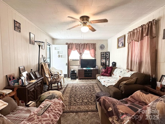 carpeted living area featuring crown molding, ceiling fan, and wood walls