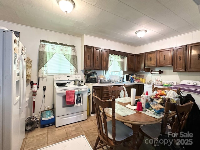 kitchen with light countertops, light tile patterned floors, white appliances, and dark brown cabinets