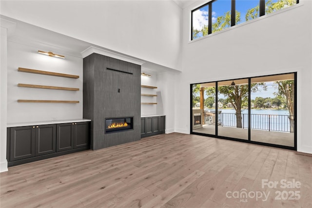 242 Shoreline Loop, Mooresville, NC 28117 - unfurnished living room with light wood-style floors, a large fireplace, healthy amount of natural light, a towering ceiling, and a water view