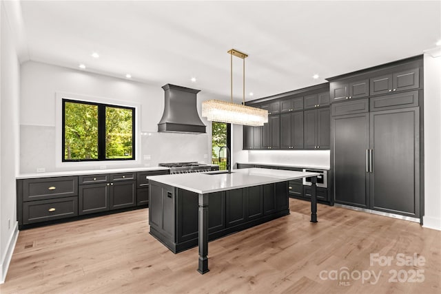242 Shoreline Loop, Mooresville, NC 28117 - kitchen featuring custom exhaust hood, light countertops, light wood-type flooring, pendant lighting, and a center island with sink