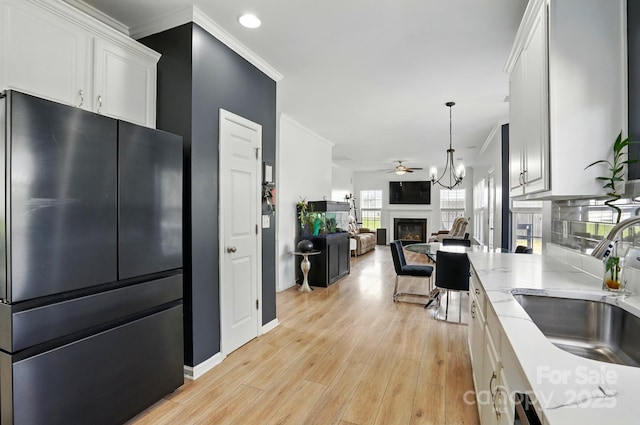 8833 Cavonnier Ln, Charlotte, NC 28216 - kitchen with freestanding refrigerator, a sink, a glass covered fireplace, white cabinetry, and ceiling fan