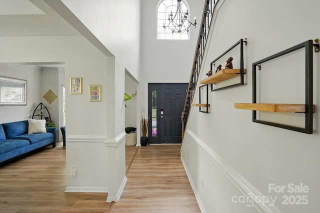 8833 Cavonnier Ln, Charlotte, NC 28216 - entryway with light wood-style flooring, baseboards, a towering ceiling, stairs, and a chandelier