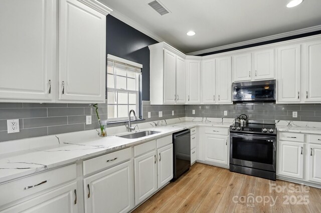8833 Cavonnier Ln, Charlotte, NC 28216 - kitchen with stainless steel appliances, a sink, white cabinetry, light wood-type flooring, and backsplash