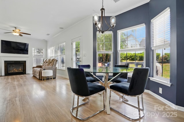 8833 Cavonnier Ln, Charlotte, NC 28216 - dining room with a chandelier, a glass covered fireplace, light wood-style flooring, crown molding, and ceiling fan