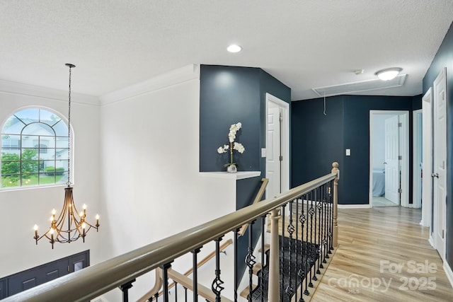 8833 Cavonnier Ln, Charlotte, NC 28216 - hallway with attic access, an upstairs landing, light wood-style floors, a textured ceiling, and a chandelier