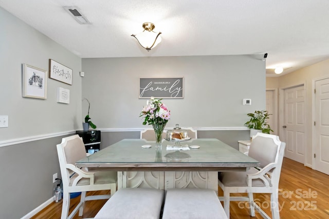 dining area with baseboards, wood finished floors, and visible vents