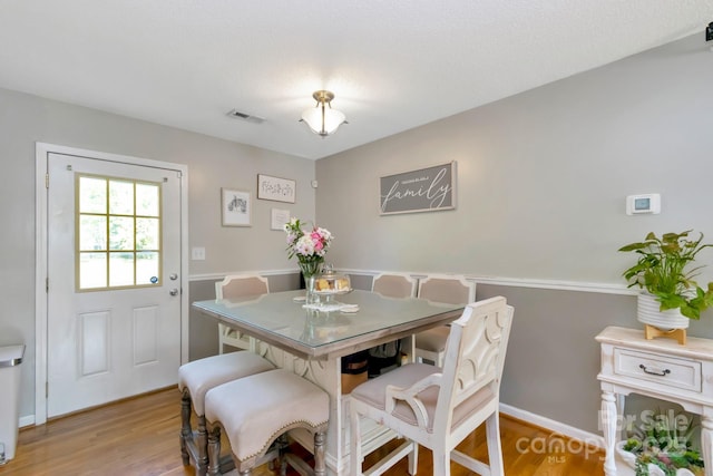 dining space with baseboards, light wood finished floors, and visible vents