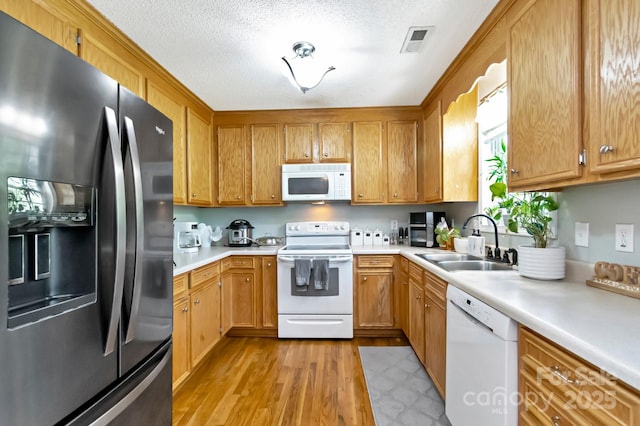 kitchen featuring a sink, light wood finished floors, white appliances, light countertops, and visible vents