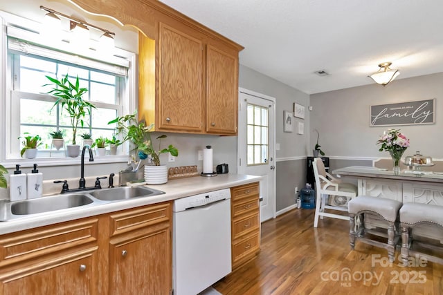 kitchen with visible vents, wood finished floors, white dishwasher, light countertops, and a sink
