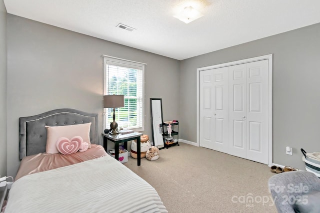 carpeted bedroom featuring baseboards, visible vents, and a closet