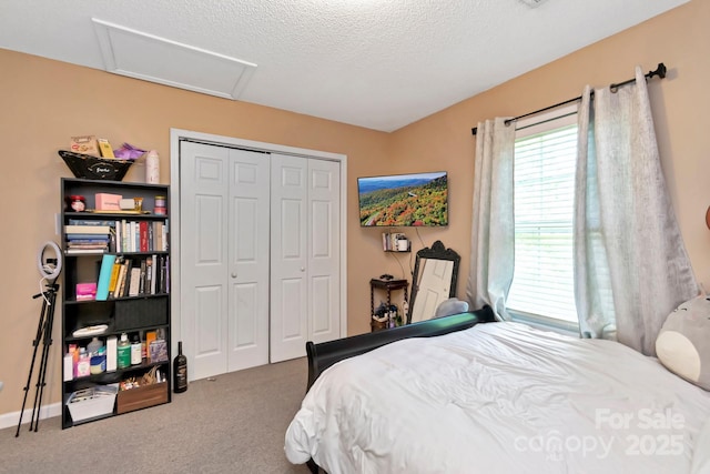 carpeted bedroom with a textured ceiling, attic access, and a closet