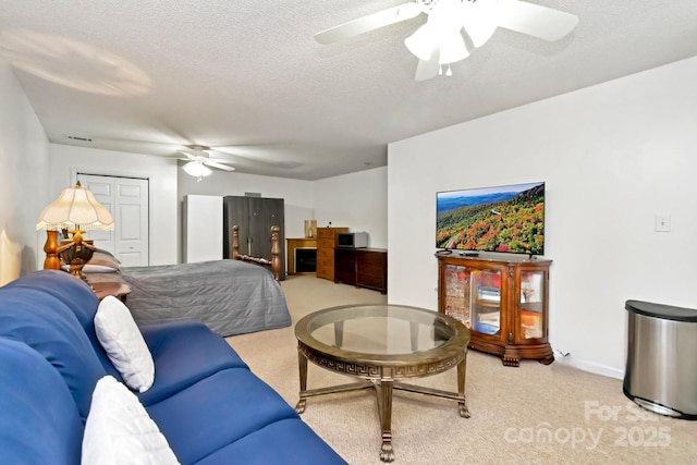 bedroom featuring ceiling fan, light carpet, a textured ceiling, baseboards, and visible vents
