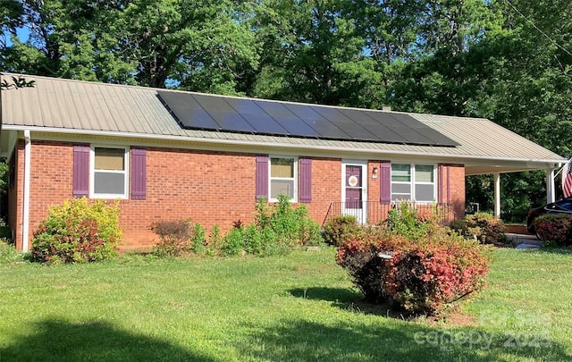 ranch-style home with brick siding, solar panels, and a front yard