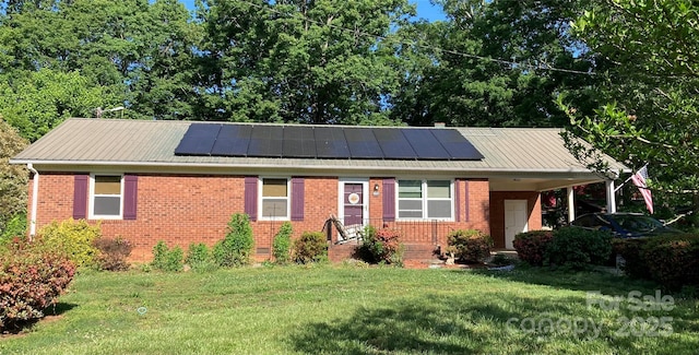 ranch-style house featuring roof mounted solar panels, metal roof, a front lawn, and brick siding