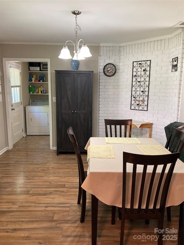 dining area featuring crown molding, brick wall, washer / clothes dryer, and wood finished floors
