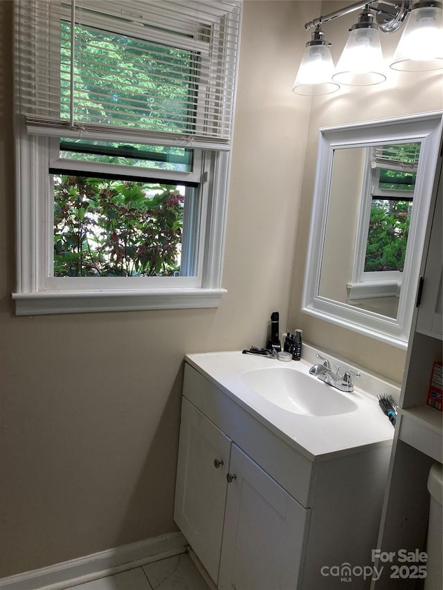 bathroom with baseboards, a healthy amount of sunlight, and vanity