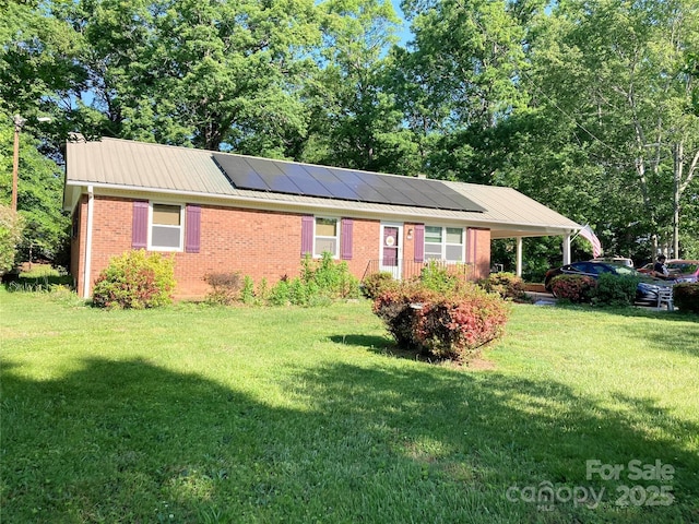 ranch-style house with brick siding, solar panels, metal roof, and a front lawn